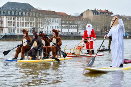 Remeros de pie vestidos como Papá Noel, renos y un ángel, cruzan el río Neckar en Heidelberg, en el suroeste de Alemania