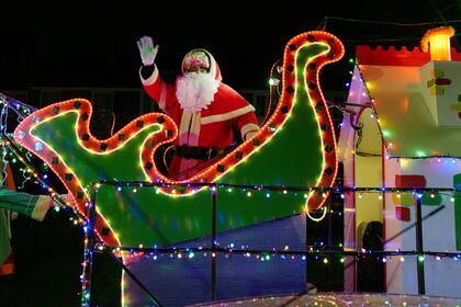 Papá Noel saluda desde un camión decorado con luces mientras se abre paso a través de la aldea de Cuxton en Kent, Gran Bretaña