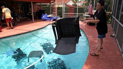 En Florida una mujer tira las mesas y sillas de su jardín para que no salgan volando con los fuertes vientos