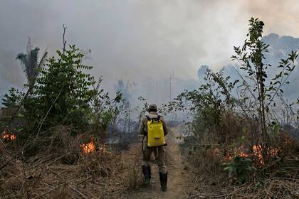 Un bombero camina por un sendero con su mochila cargada de agua en el Parque Nacional Jacunda