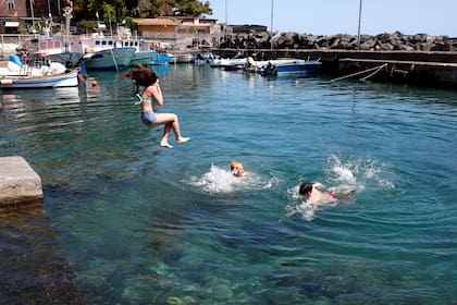 Lo niños juegan en el agua en el pueblo pesquero de San Giovanni li Cuti, cerca de Catania