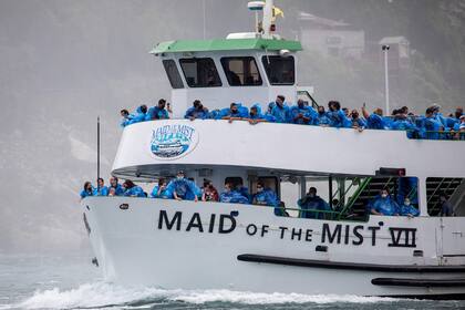 Asomados en la borda, los turistas que salieron desde el lado estadounidense se amontonan para obtener la mejor foto en el Niágara; los barcos ocupan el 50% de su capacidad por el coronavirus