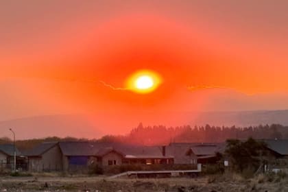 Atardecer teñido de rojo, con el humo marcando el horizonte de la comarca andina