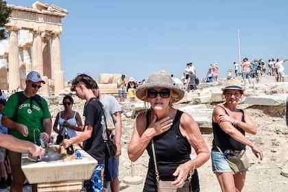 Los turistas se refrescan frente al Partenón, en Atenas, durante la ola de calor de julio.