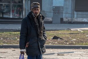 Aturdido y cubierto de sangre seca, un hombre mira fijamente a la cámara mientras camina hacia un puesto de control que conduce desde la ciudad asediada de Mariupol al territorio controlado por la República Popular de Donetsk el 23 de marzo de 2022.