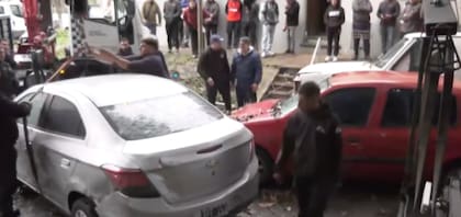 Autos que se desplazaron por la fuerza del temporal y el agua bloquean una calle en San Martín