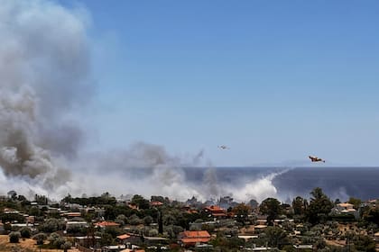 Aviones de bomberos lanzan agua mientras combaten un incendio en la zona costera de Palaia Fokaia, al sur de Atenas, el jueves 26 de junio de 2025. (AP Foto/Giorgos Delveroudis)