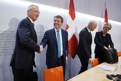 Axel Lehmann, presidente de Credit Suisse, y Colm Kelleher, presidente de UBS, se dan un apretón de manos junto al presidente federal suizo, Alain Berset, y la ministra suiza de Finanzas, Karin Keller-Sutter, al final de una conferencia de prensa el domingo 19 de marzo de 2023, en Berna, Suiza.