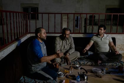 Aziz al-Asmar, izquierda, con amigos compartiendo mate en su casa en Binnish, Siria