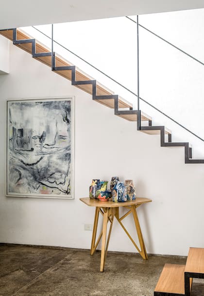 Bajo la escalera (que también fue diseñada por Vale) un grupo de jarrones de la serie que ella misma modela y pinta junto a una obra de Joaquin Boz.