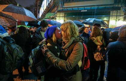 Bajo la lluvia, dos jóvenes se besan en la puerta de La Biela