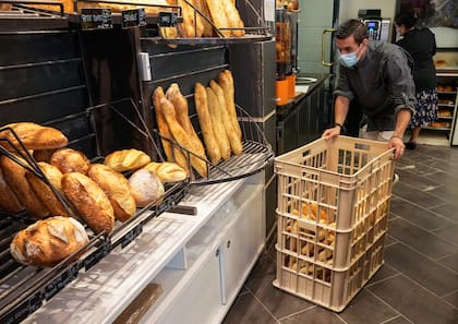 Baker Ludovic Laurent, con un canasto con baguettes en su negocio en Versailles; la guerra en Ucrania tensionará los precios de la harina de trigo, ya que el país europeo es uno de los principales productores. (AP Photo/Michel Euler