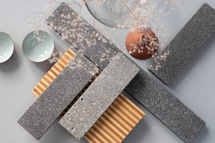 Baldosas BioBasedTiles® desarrolladas por Biomason y FRONT, fabricadas con biocemento mediante un proceso de cultivo a partir de microorganismos. Estos actúan como “obreros biológicos” que endurecen los agregados a temperatura ambiente, eliminando el uso de hornos y reduciendo a cero las emisiones de CO2