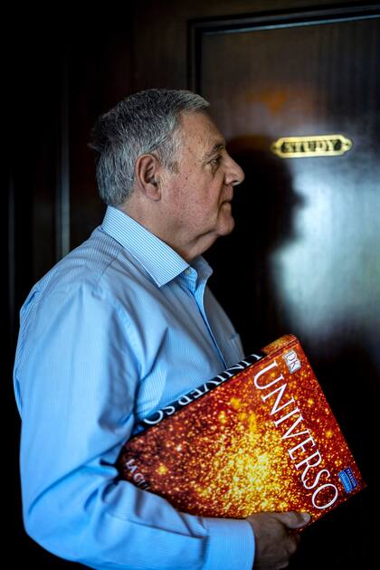 Ballester Olmos, con uno de los volúmenes de su biblioteca, ante la puerta de su estudio, en su casa de Valencia. Foto: RAÚL BELINCHÓN/ El País