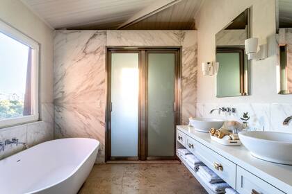 Bañadera exenta de resina acrílica (Welttechnik). Toallas (Luna Deco) y vela con vaso espejado (Bohemia Velas).