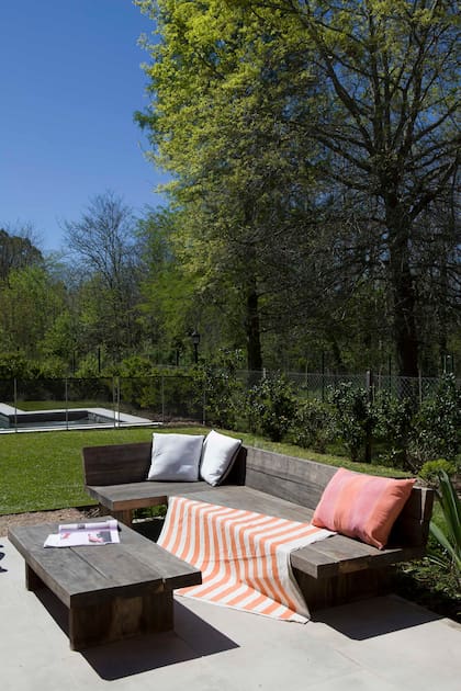 Bancos y mesas de madera (Lolo & Co) con manta y almohadones (Mercedes Segura Deco).