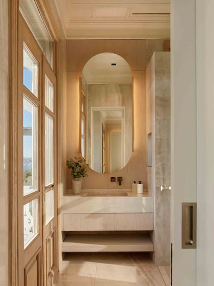 Baño en suite con vistas al mar. Revestimiento en piedra clara y grifería minimalista realzan el lujo.