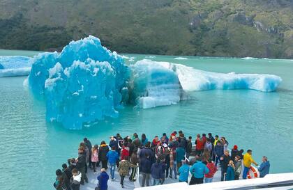 La cubierta del Mar Turquesa se aproxima a un glaciar y se cubre de tripulantes, cámara en mano.