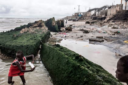 Niños juegan dentro de las ruinas de la antigua mezquita a lo largo de la costa erosionada en Bargny, Senegal