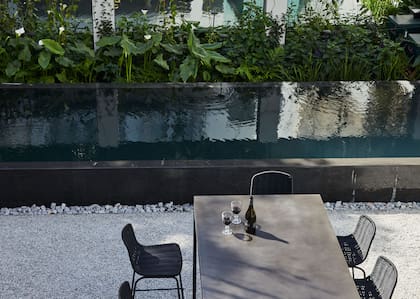 Barra en metal y hormigón ennegrecido (Kallos Turin) se ubicó perpendicular a la pileta que toma el largo del jardín. Banquetas 'Lapala' (Viaduct Furniture Londres).