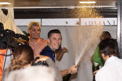 Bartolomé Castagnola (h.) sacude la botella y no "perdona" a nadie en la carpa de los palenques; su hermano Camilo disfruta atrás.