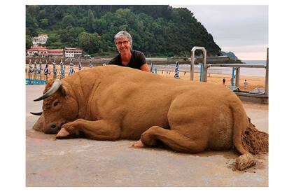 Bastarrika junto a un toro de tamaño real hecho en arena en el malecón de la playa Zarauz