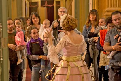 Madres y padres esperan en el foyer de ingreso al teatro Colón, mientras se toman selfies con sus niños, que no superan los dos años