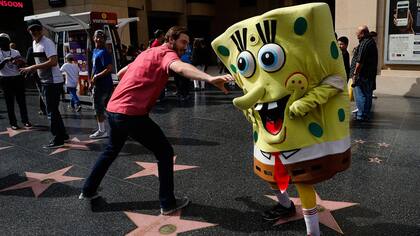 Belnarr Golden, vestido con un traje de Bob Esponja, esquiva a un turista tratando de tirar la nariz de su traje en Hollywood Boulevard, en Los Ángeles.