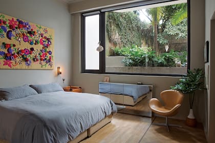 Un colorido tapiz traído del Norte, un par de mesas de madera y cuero de Eugenio Aguirre y una cómoda con puertas de vidrio, algunos de los objetos que sobresalen en el dormitorio en suite. 