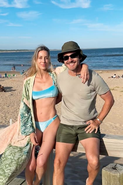 Benja y Anita sonríen a cámara. Ella acompañó su bikini con un kimono con arabescos, mientras él optó por shorts de baño y sombrero coordinados