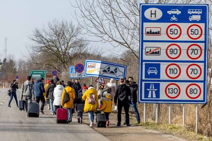 Un grupo de personas camina con sus pertenencias en el cruce fronterizo de Astely-Beregsurany huyendo de Ucrania el 25 de febrero de 2022 en Beregsurany, Hungría. (Foto de Janos Kummer/Getty Images)