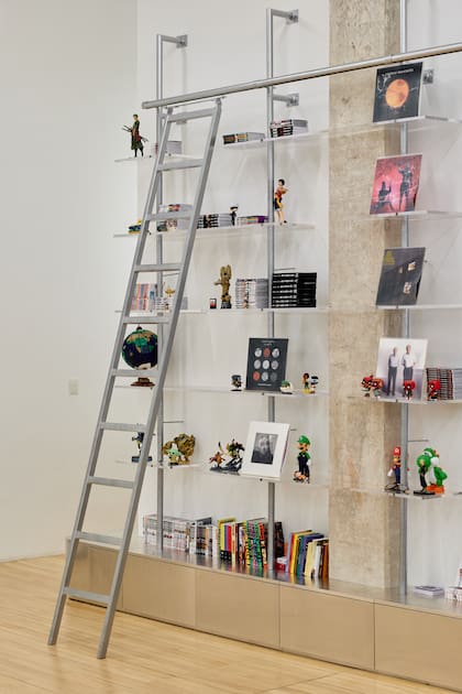 Biblioteca de caños de acero, estantes de acrílico y rack inferior de MDF enchapado en aluminio (Wollstudio).