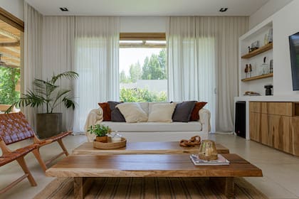 Biblioteca de MDF pintado combinado con estantes y puertas de petiribí arenado. Sillón ‘Pampa’, sillones ‘Piet’ de paraíso y cuero, mesas de centro de petiribí y alfombra.