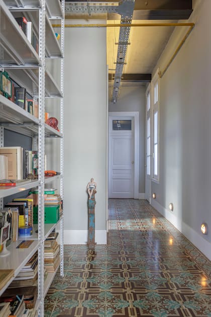 Biblioteca realizada con estantes industriales de chapa (Callegari Minervini & Associati). Para iluminar, bandeja metálica con spots.