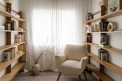 Bibliotecas diseñadas a medida (Esto Es Regio), sillón (Lu Picco Living). En los estantes, objetos de cerámica (Blau). Vasija (Rancho Deco).