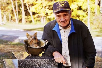 Bill Wynne junto a un monumento en homenaje a su perra Smoky, que fue levantado en un parque de Cleveland en el año 2005 por veteranos de guerra