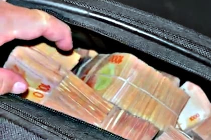 Billetes dentro de una valija, en la fila de una cueva de Retiro