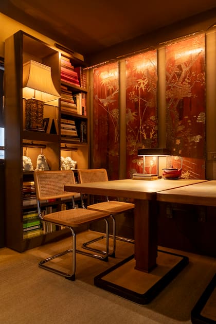 Biombo del siglo XVIII, en madera y laca, regalo de Bárbara Diez. "Es de lo mejor que tengo en la casa. Lo desarmé, le saqué las bisagras y lo colgué como un cuadro". Mesas de madera y pergamino de la firma Nordiska Kompaniet que pertenecieron a un restaurante en los 50, acompañadas por sillas ‘Cesca’. Tetera japonesa antigua de hierro fundido, traída a Argentina en los 60.