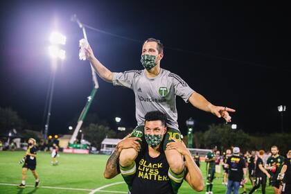 Blanco figura, con barbijo y en hombros de un compañero