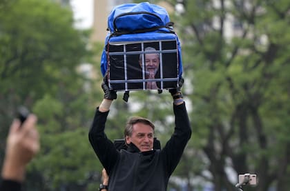 Bolsonaro alza una mochila con una imagen de Lula preso durante un acto en San Pablo el día previo a las elecciones