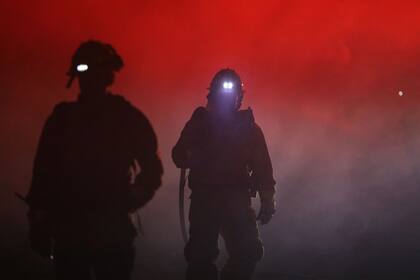 Bomberos envueltos en humo mientras combaten un incendio forestal en California