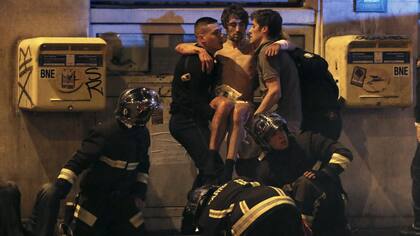 Bomberos franceses socorren a un joven herido en el teatro Bataclán, luego de la toma de rehenes