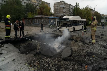 Bomberos y agentes de la policía trabajan en el sitio donde una explosión creó un cráter en una calle tras un ataque ruso en Dnipro, Ucrania, el lunes 10 de octubre de 2022. (AP Foto/Leo Correa)