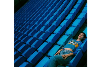 Con la camiseta, cómoda y recostada, la adolescente posa en la platea de su casa, la Bombonera.