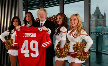 Boris Johnson, entonces alcalde de Londres, en el centro, y cuatro de las animadoras de los 49ers posan para los medios de comunicación mientras el alcalde sostiene una camiseta del equipo con su nombre en el Ayuntamiento de Londres el martes 26 de octubre de 2010.