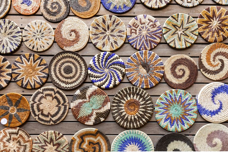 Una jirafa come hojas de un arbusto y una muestra de cestería típica de la zona trabajada a mano por las mujeres locales. (Foto: Estrella Herrera)