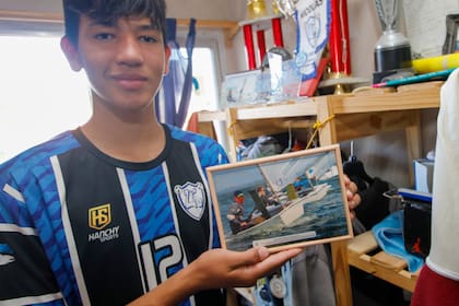 Brandon muestra una foto de uno de sus viajes; detrás se ven los trofeos que ganaron él y sus hermanos