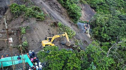 Brigadistas intentan rescatar a 31 personas que quedaron sepultadas bajo un deslizamiento de tierra cuando viajaban en un bus y una moto
