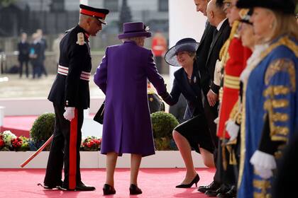 La primera ministra británica, Theresa May, saluda a la reina Isabel II sin romper el protocolo