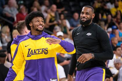 Bronny James y LeBron James calientan antes de un encuentro de pretemporada ante los Suns. (AP Foto/William Liang, Archivo)